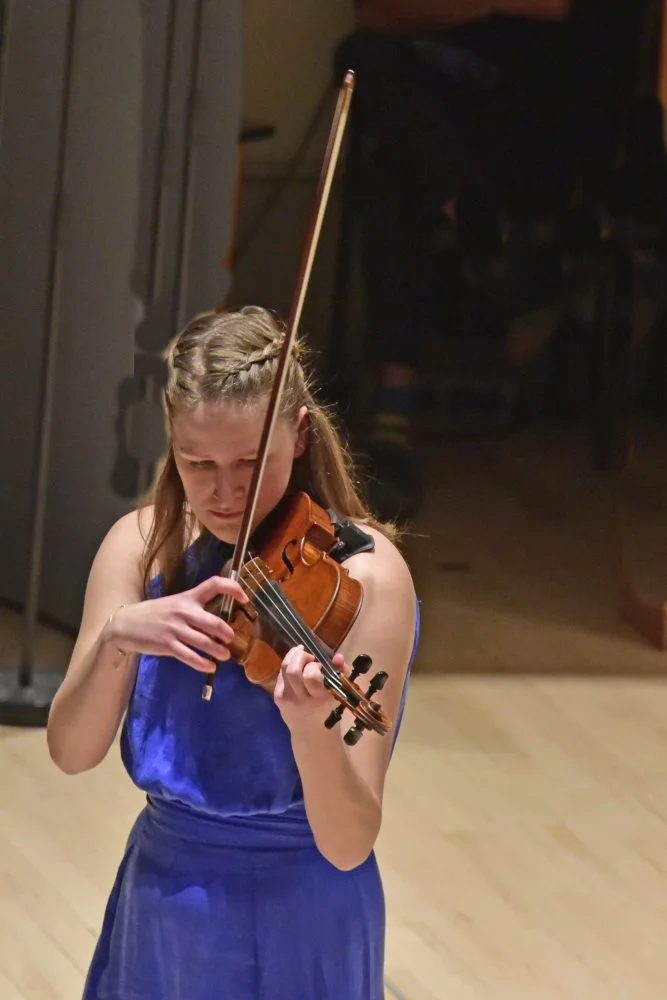 Niki speelt geconcentreerd viool tijdens een klassiek concert