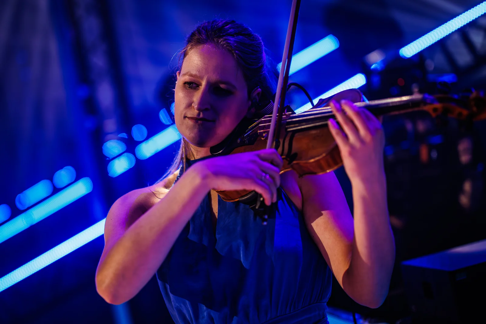 Niki speelt viool tussen blauwe podiumlichten